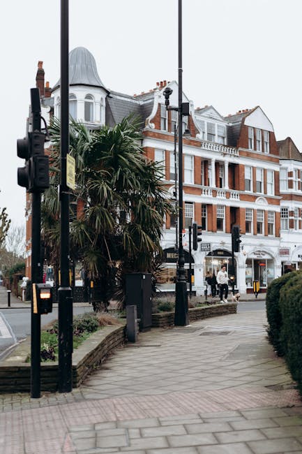 The image shows a street scene outside a large, multi-storey Victorian-style building with red brick and white trim, characteristic of residential or commercial property in Balham. In the foreground,